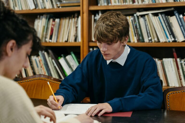 Photo de deux individus étudiant en bibliothèque.